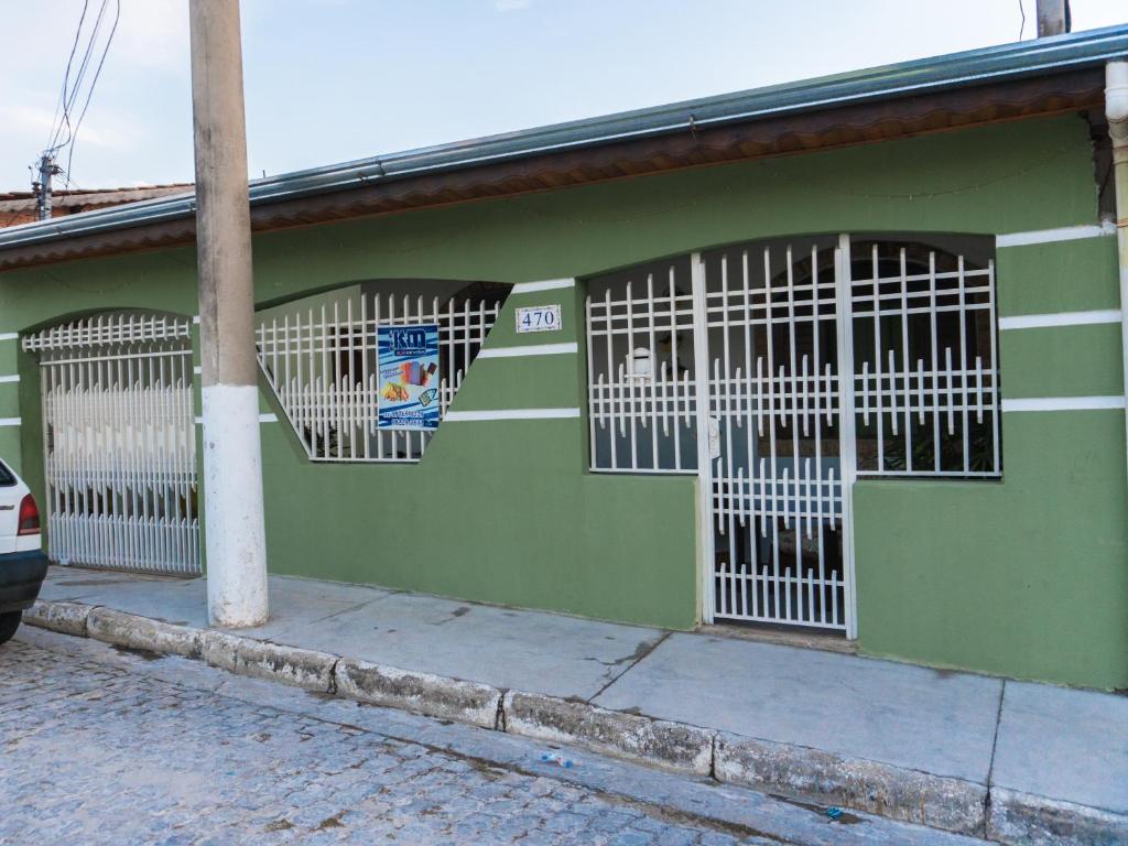 ein grünes Gebäude mit weißen Toren an der Seite in der Unterkunft Casa & Hospedagem Carol in Cachoeira Paulista