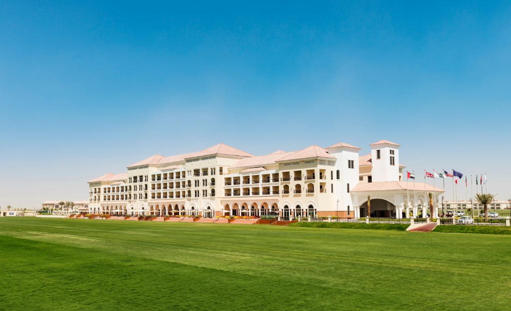 a large building with a green field in front of it at Al Habtoor Polo Resort in Dubai