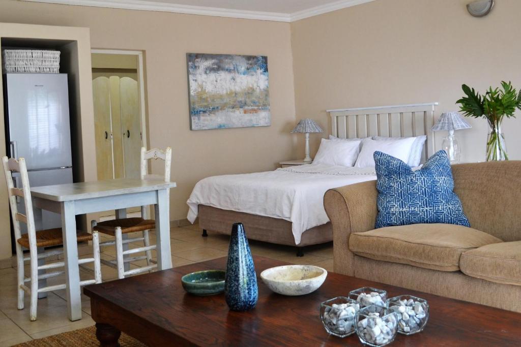 a bedroom with a bed and a couch and a table at Claire's Deluxe Studio Apartment - SOLAR in Ballito
