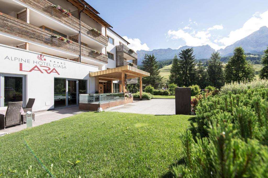 vista sulla parte anteriore di un edificio con prato di Alpine Hotel Ciasa Lara a La Villa