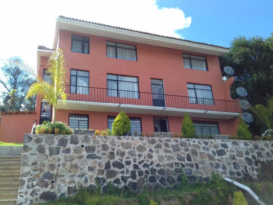 ein großes orangefarbenes Gebäude mit einer Steinmauer in der Unterkunft Casa Amelia Hotel Boutique in Zacatlán