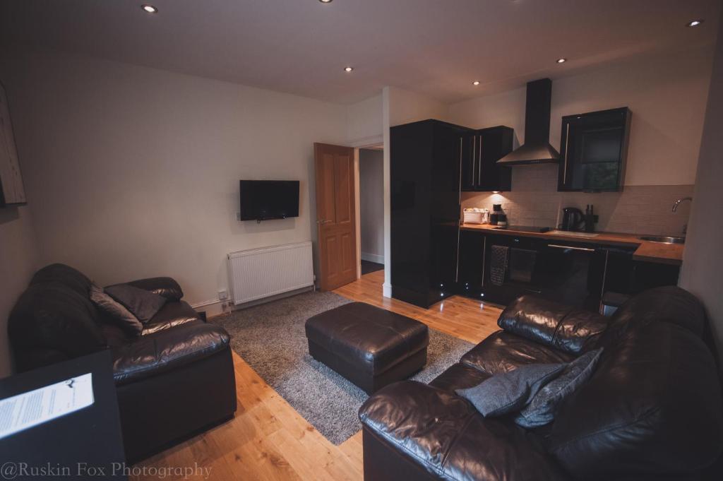 uma sala de estar com dois sofás de couro e uma cozinha em Apartment C em Aberdeen