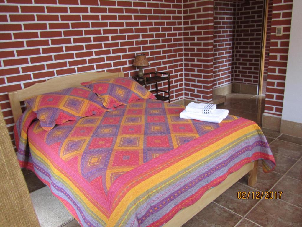 a bed with a colorful blanket on top of it at El Encanto Sorata in Sorata