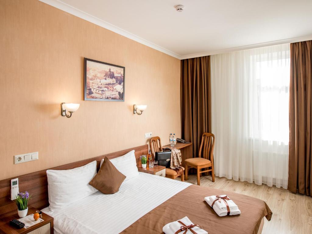 een hotelkamer met een groot bed en een bureau bij Hotel&SPA Pysanka, Готель Писанка, 3 сауни та джакузі - індивідуальний відпочинок у СПА in Lviv