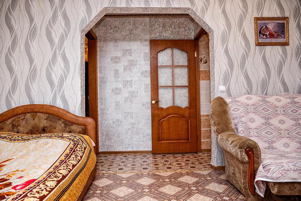 a bedroom with a bed and a wooden door at Apartment on Krasnoarmeyskaya 137 in Kemerovo
