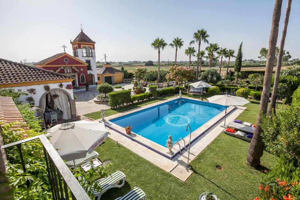 an overhead view of a swimming pool in a yard with umbrellas at Casa de Campo con Piscina en Sevilla en los Palacios y Villafranca in Los Palacios y Villafranca