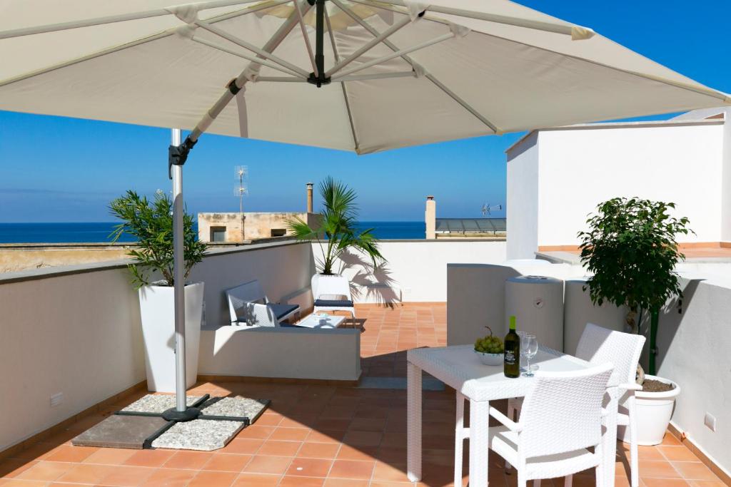 un patio con sombrilla, mesa y sillas en ZIBIBBO SUITES & ROOMS - Aparthotel in Centro Storico a Trapani en Trapani