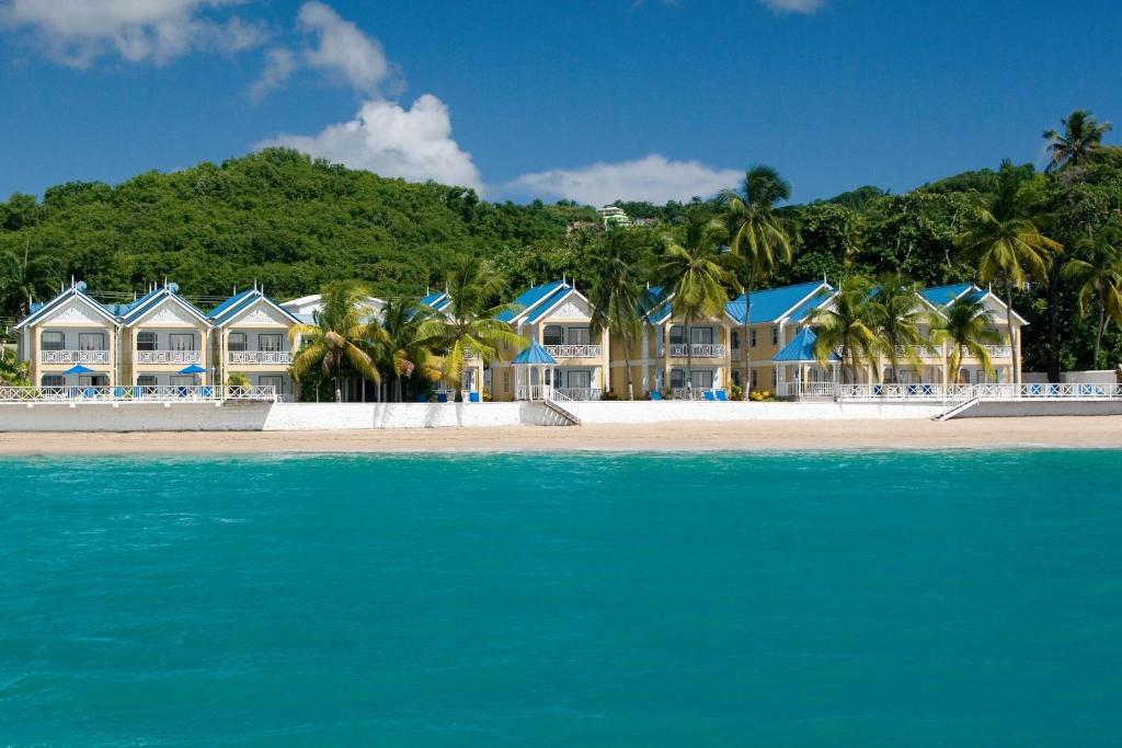 a row of houses on a beach next to the water at Villa Beach Cottages in Castries