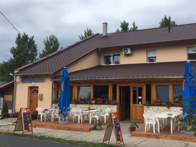 a restaurant with tables and chairs and blue umbrellas at Balaton Panzió in Balatonberény