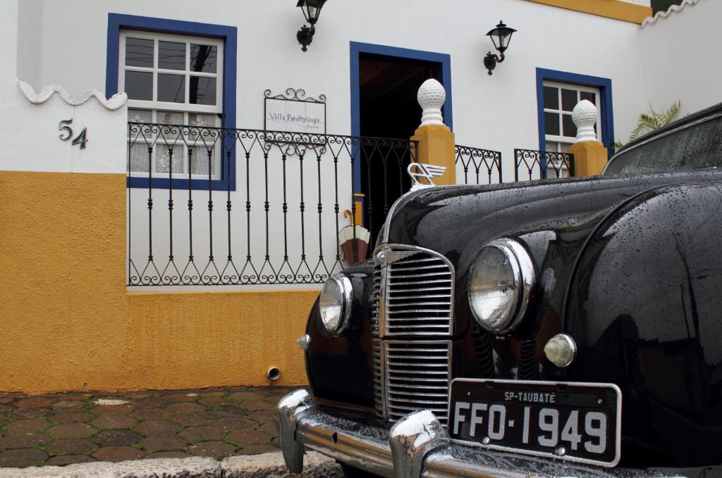 Pousada Villa Parahytinga في ساو لويز دو بارايتنغا: سيارة سوداء قديمة متوقفة أمام مبنى