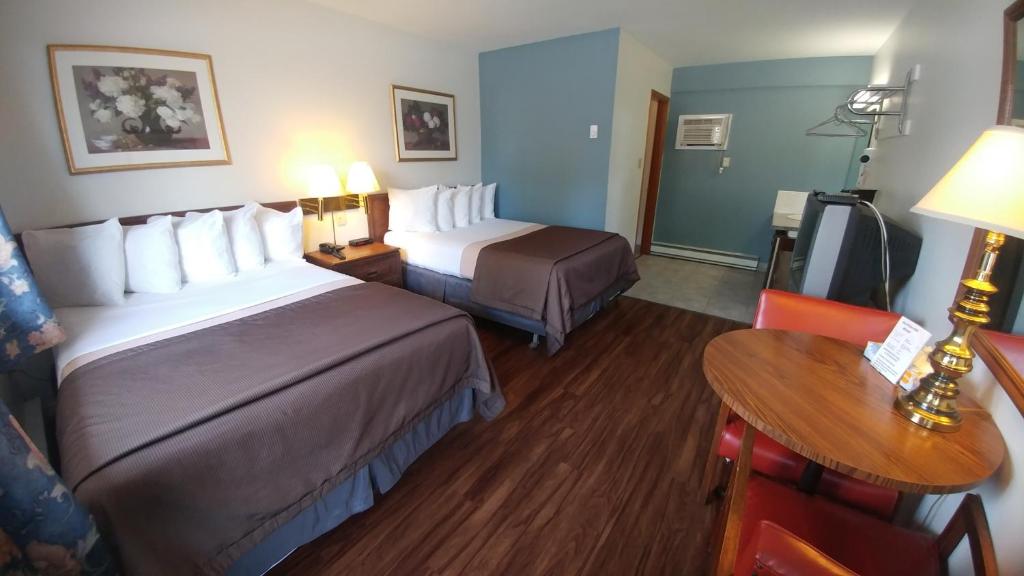 a hotel room with two beds and a table at Northlander Motel in Sault Ste. Marie