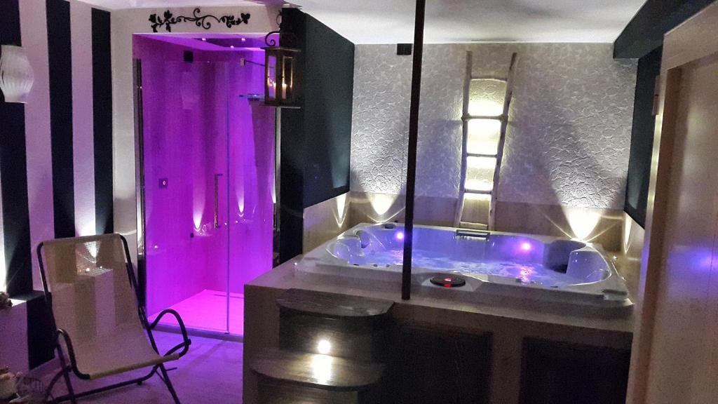 uma casa de banho com uma banheira com luzes roxas em Piccolo Relais Galletto di Marzo Spa e relax solo per due em Paciano