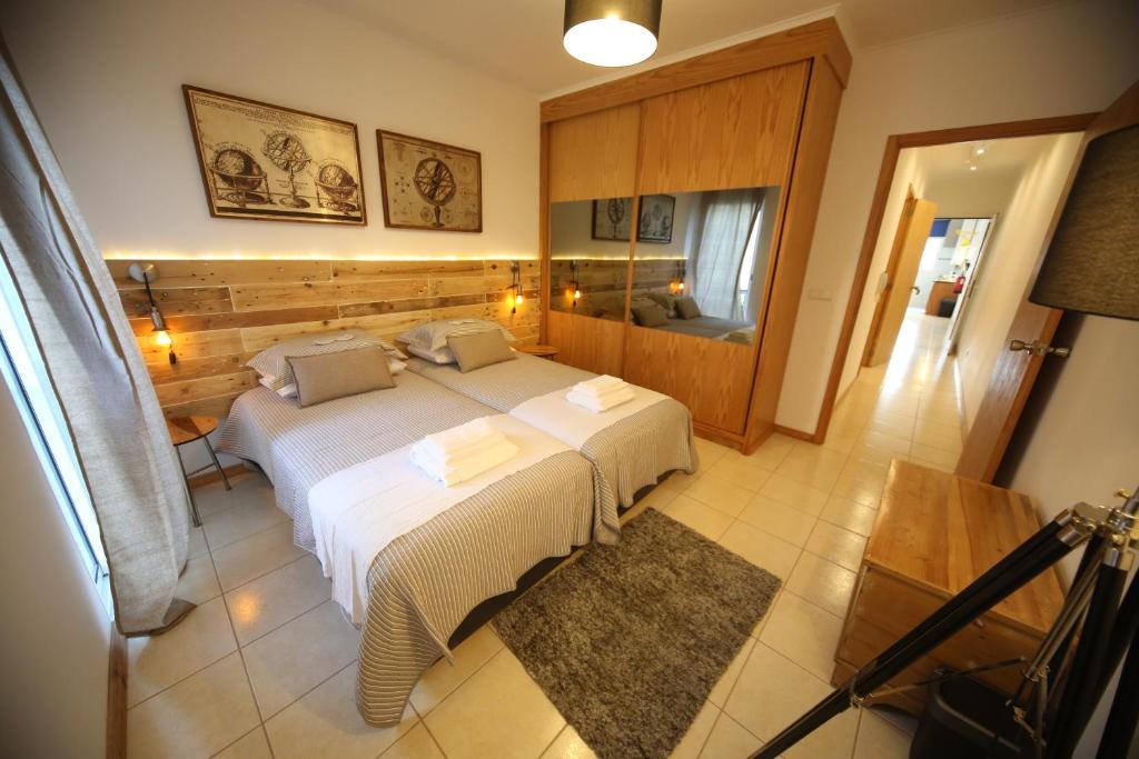 ein Schlafzimmer mit einem großen Bett und einem Spiegel in der Unterkunft Ap´s do Forte in Ponta Delgada
