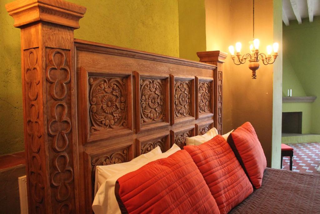 a wooden bed with orange pillows in a room at Hotel Galería in San Miguel de Allende