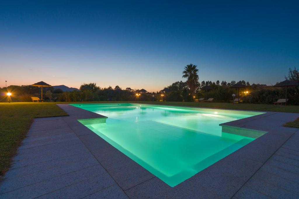 a swimming pool with green lighting at night at Janas Country Resort in Mores