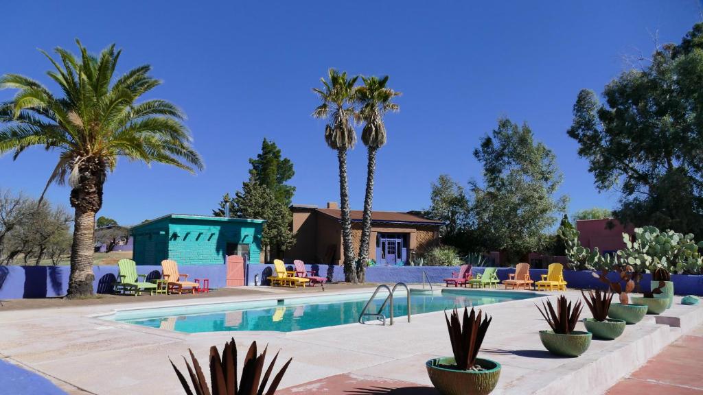 a swimming pool with palm trees and a resort at Rancho de la Osa Guest Ranch in Sasabe