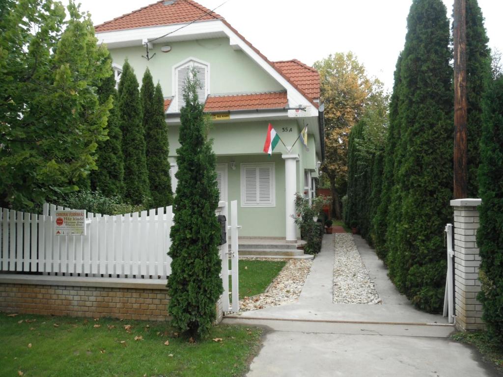 a white fence in front of a white house at Csokonai guesthouse in Zamárdi