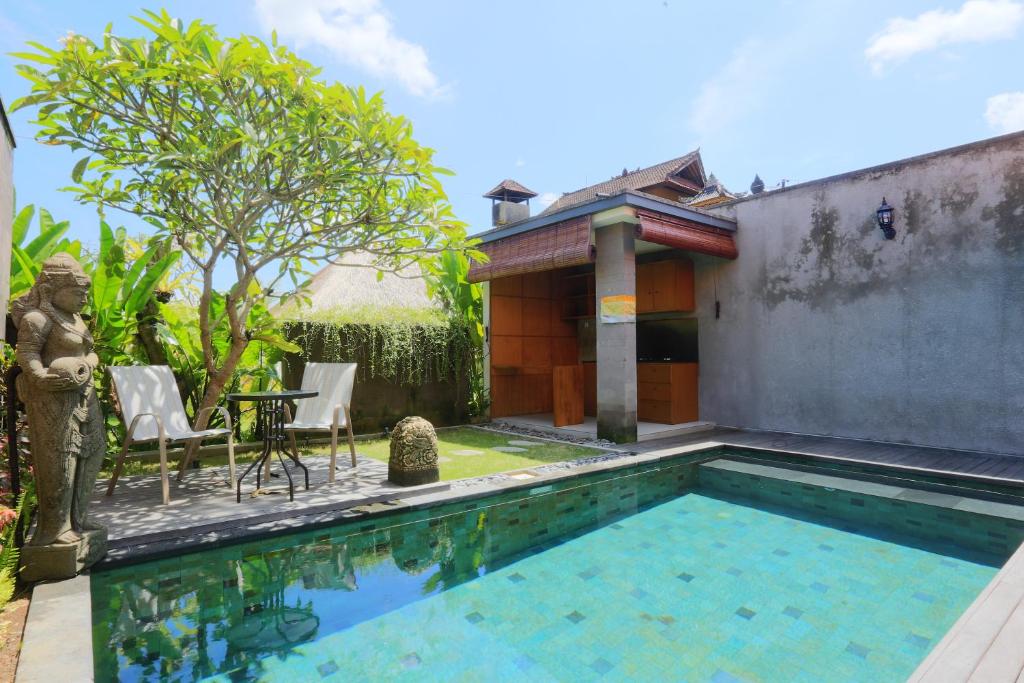 a pool with a table and chairs next to a house at Ume Sri Villas Ubud in Ubud