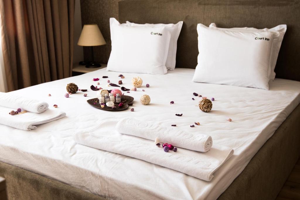 uma cama com lençóis brancos e flores em Court Inn em Panagyurishte