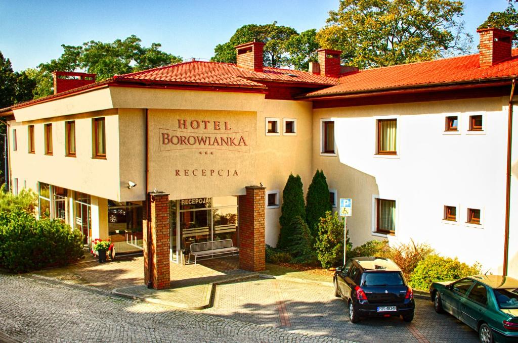 un hotel con coches estacionados frente a un edificio en Hotel i Restauracja Borowianka en Ostrów Wielkopolski