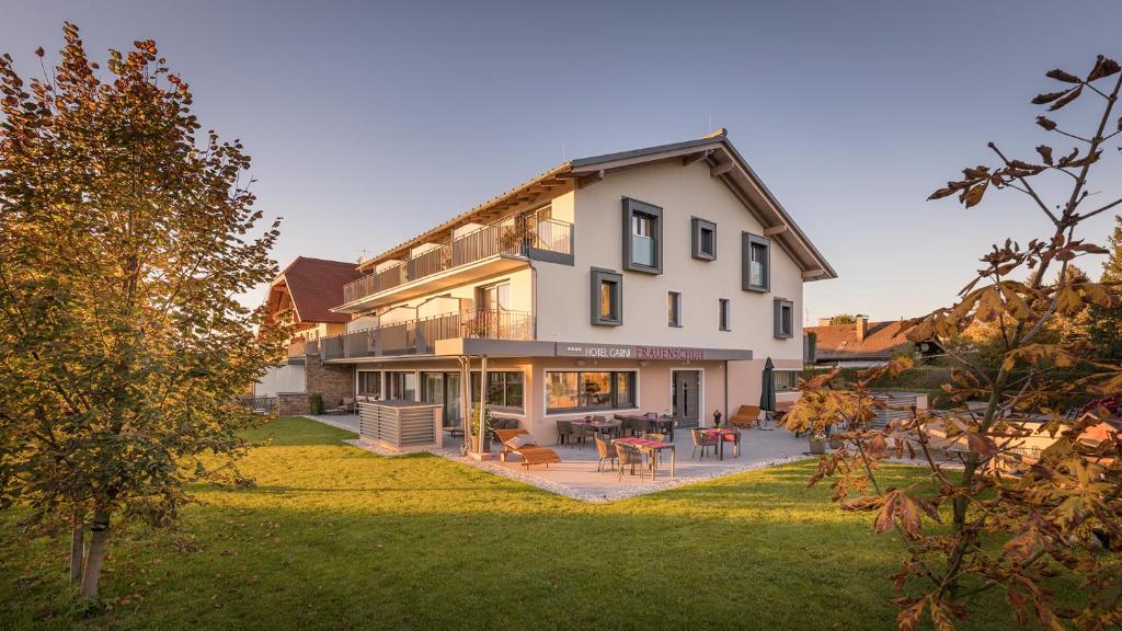 uma grande casa branca com um pátio e um quintal em Hotel Frauenschuh Garni em Salzburgo