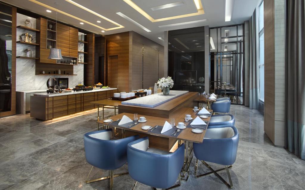 A bright dining room with blue chairs, a buffet-style counter, and tall windows.