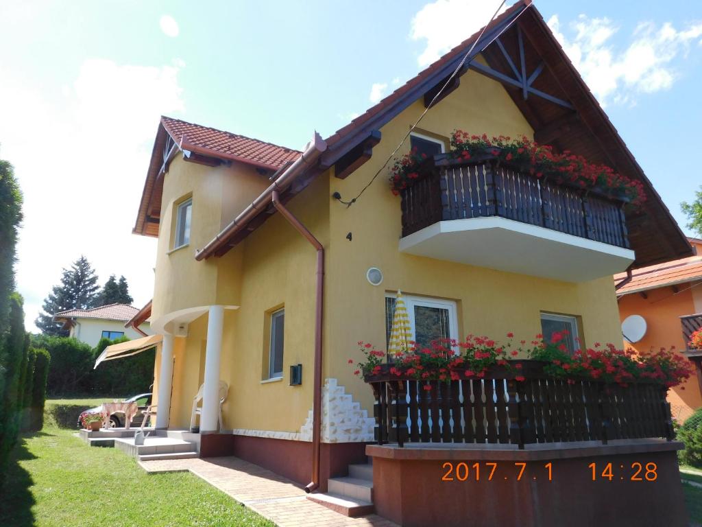 a yellow house with a balcony and flowers on it at Akácfa Hortenzia Apartman in Zalakaros