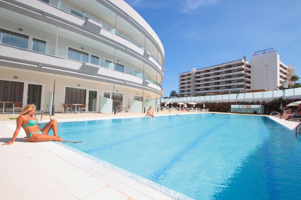 a woman sitting on the edge of a swimming pool at HL Suitehotel Playa del Inglés - Adults Only in Playa del Ingles