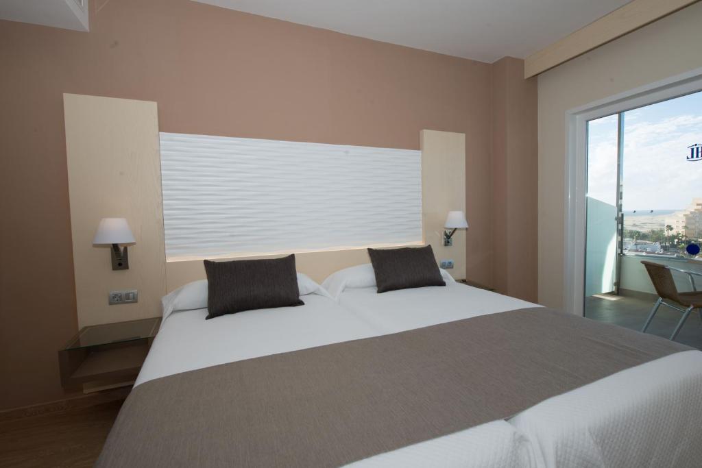 a bedroom with a large bed with a large window at HL Suitehotel Playa del Inglés - Adults Only in Playa del Ingles