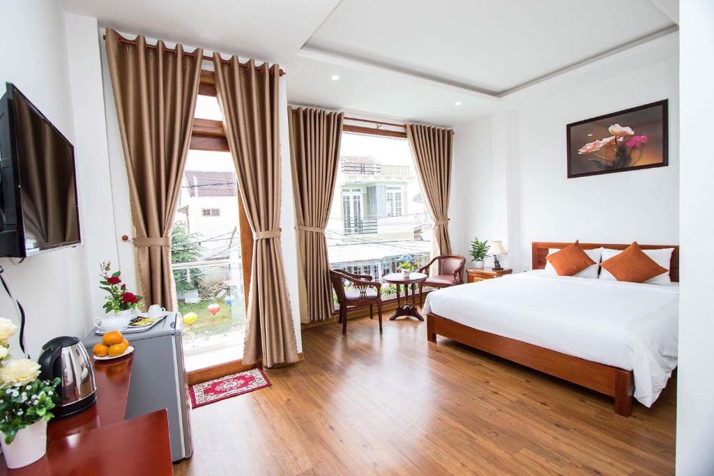 een slaapkamer met een bed, een tafel en een televisie bij Lantern Riverside Hoi An in Hội An