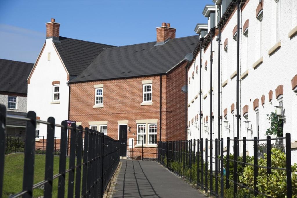 a row of brick houses with a black fence at DBS Serviced Apartments - The Stretton in Castle Donington