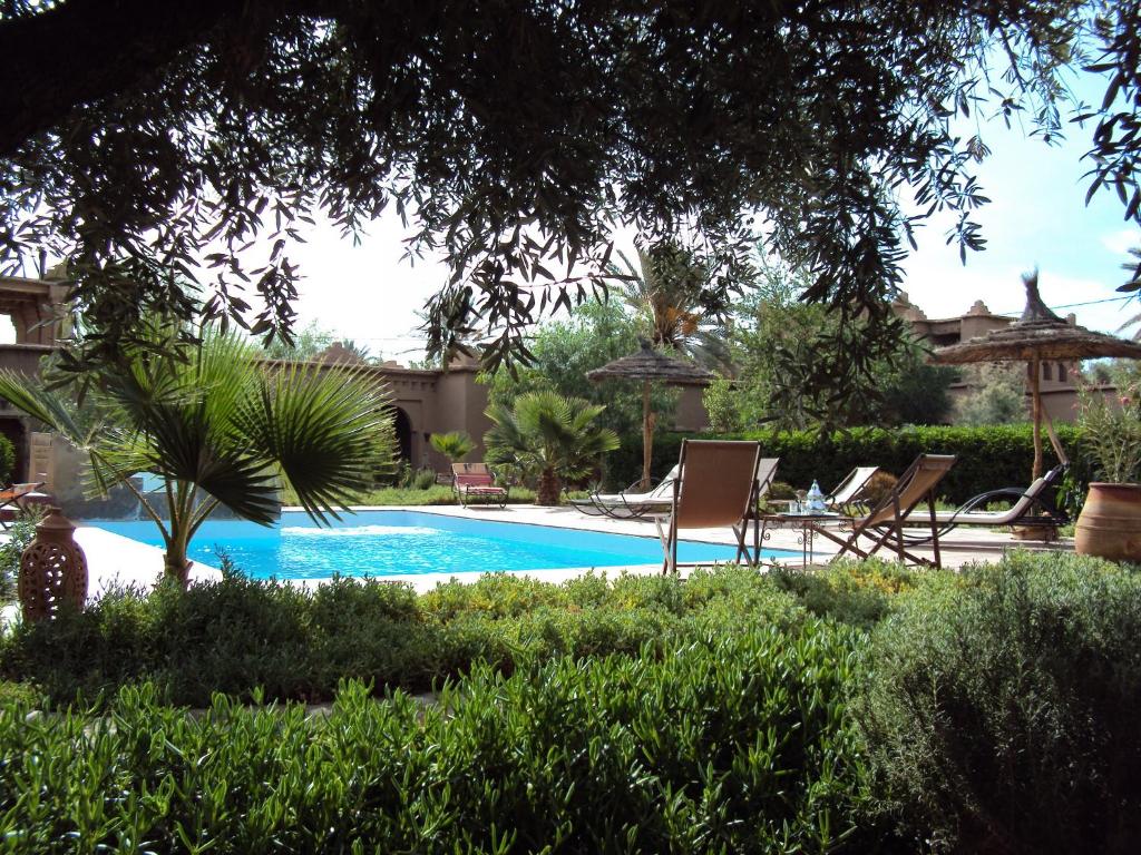 una piscina en un patio con sillas y árboles en Dar Lorkam, en Skoura