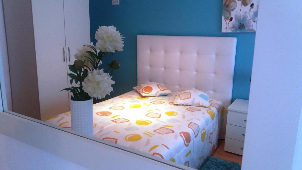 una camera da letto con un letto e un vaso di fiori di Apartamentos 7 Saias - Centro a Nazaré
