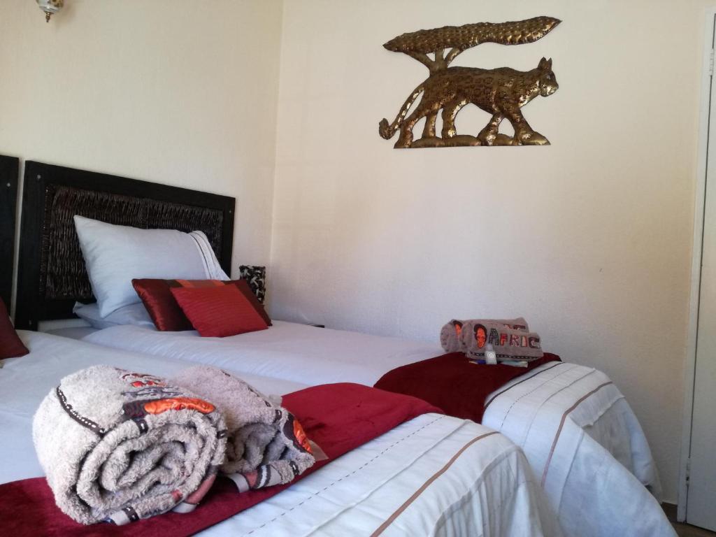 a bedroom with two beds and a statue of a wolf on the wall at All over Africa Guest house in Kempton Park