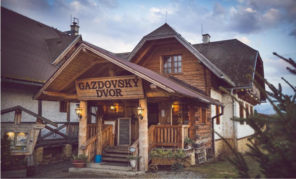 une cabane en rondins avec un panneau à l'avant de celle-ci dans l'établissement Gazdovský dvor B&B s Mini Wellness, à Bešeňová