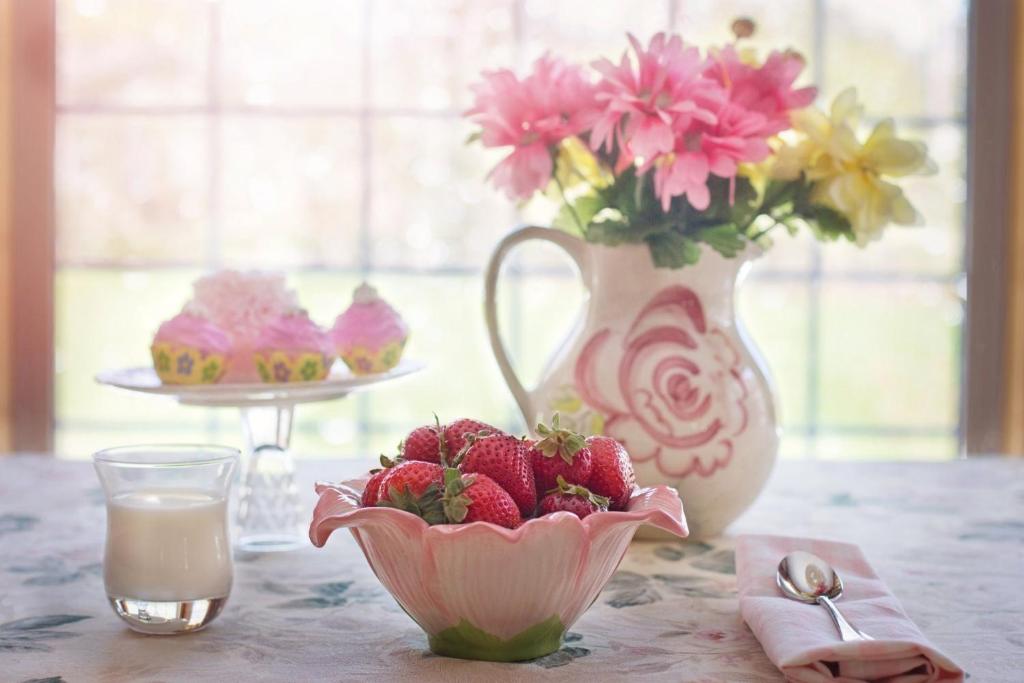 een tafel met een vaas met bloemen en een kom aardbeien bij Casa Florea in Avrig