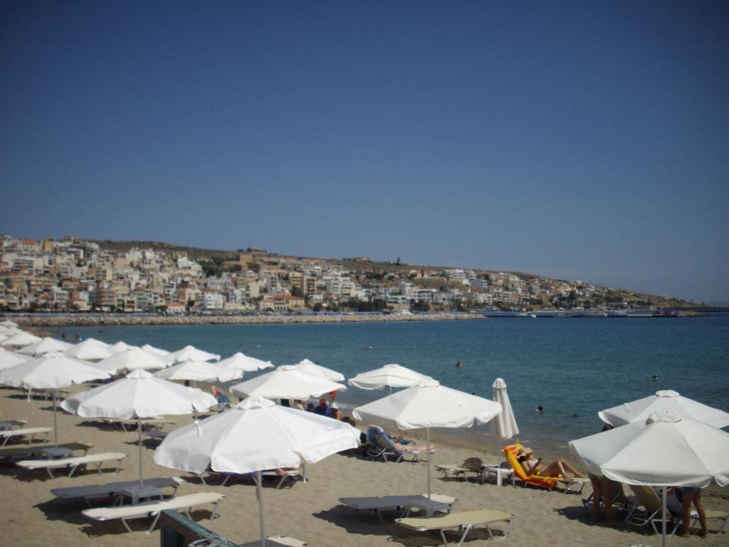 a group of white umbrellas on a beach at Anna in front of the sea Apartment in Sitia