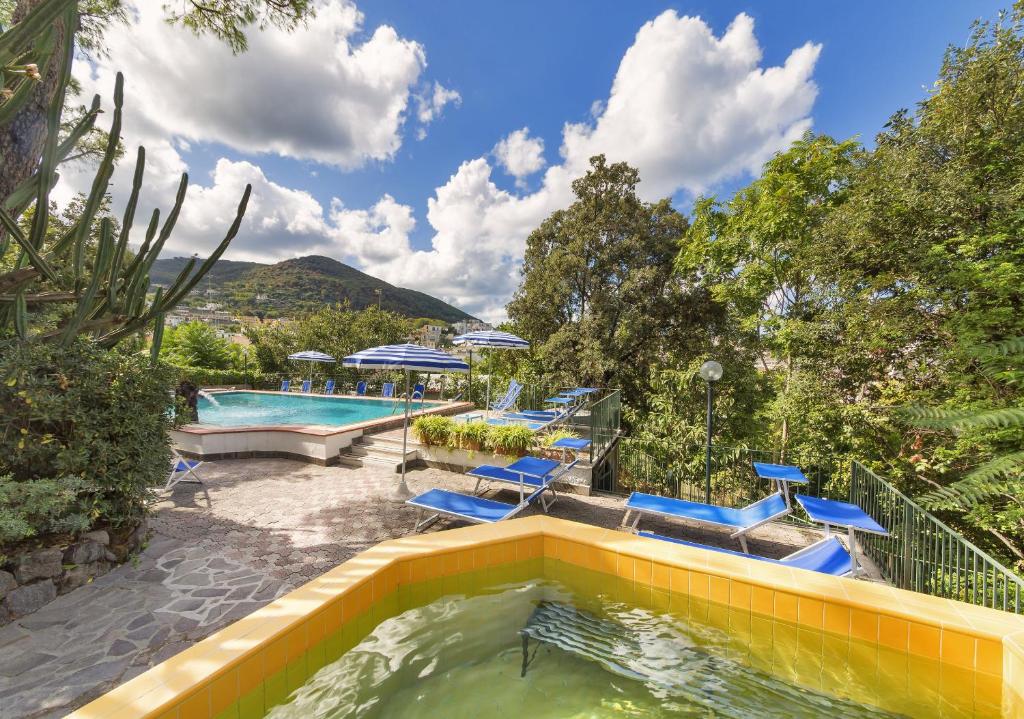 a swimming pool with blue chairs in a backyard at Hotel Vittoria in Ischia
