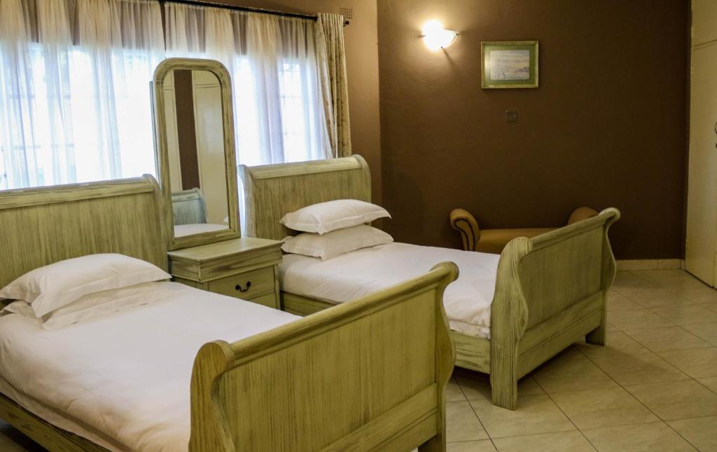 een hotelkamer met 2 bedden en een spiegel bij The White House of Victoria Falls in Victoria Falls