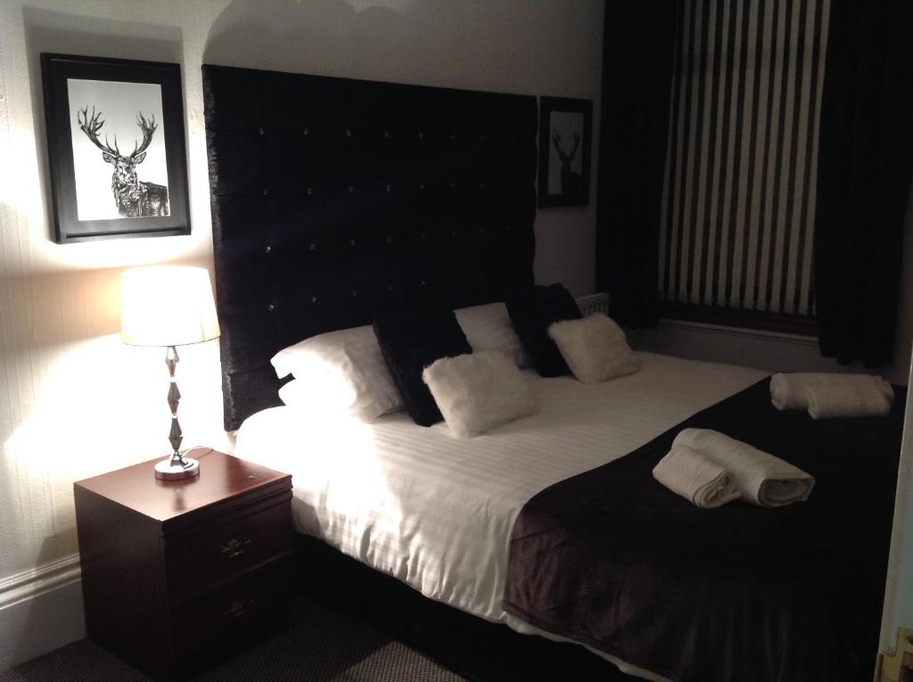 a bedroom with a bed with a black headboard and a lamp at Abbey Guest House in Peterhead