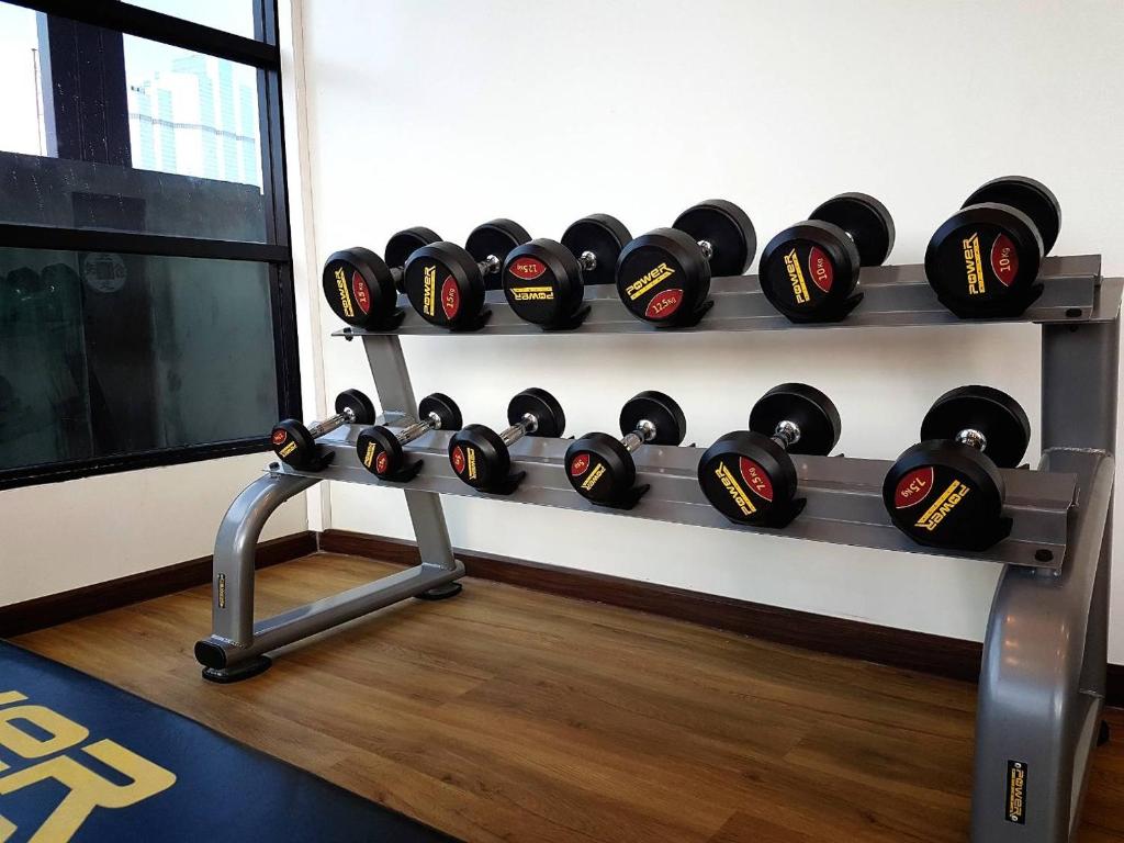 A dumbbell rack in a compact gym with a window and wood-look flooring.