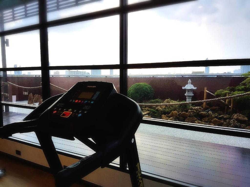 A treadmill in front of windows overlooking a landscaped rooftop and city skyline.