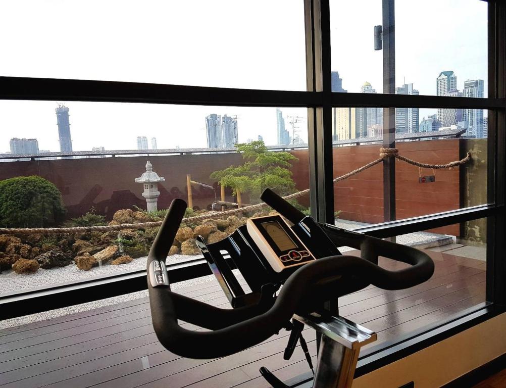 An exercise bike positioned beside floor-to-ceiling gym windows.