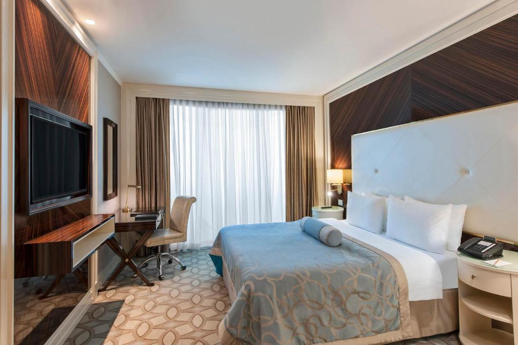 a hotel room with a bed and a flat screen tv at Elite World Istanbul Florya in Istanbul