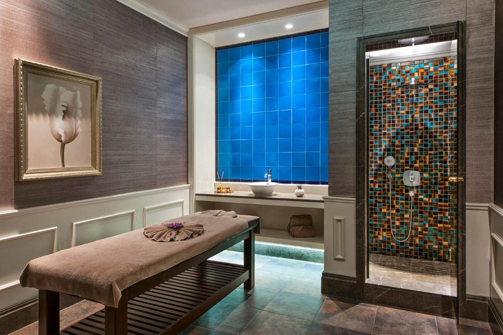 a bathroom with a shower with a bench and a sink at Elite World Istanbul Florya in Istanbul