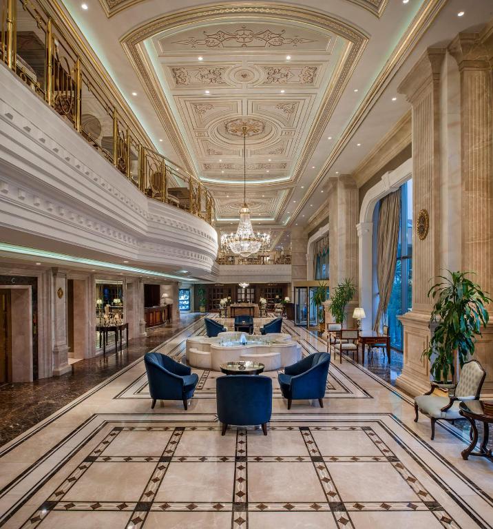 a lobby with blue chairs and a large ceiling at Elite World Istanbul Florya in Istanbul