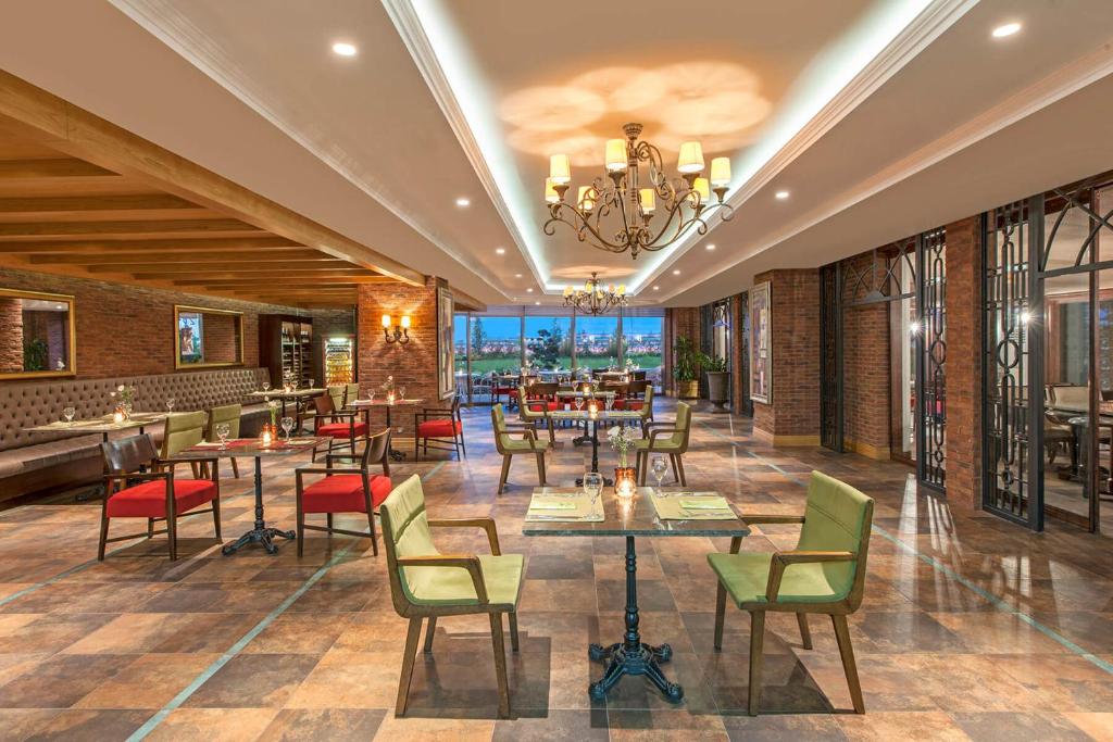 a restaurant with tables and chairs and a chandelier at Elite World Istanbul Florya in Istanbul