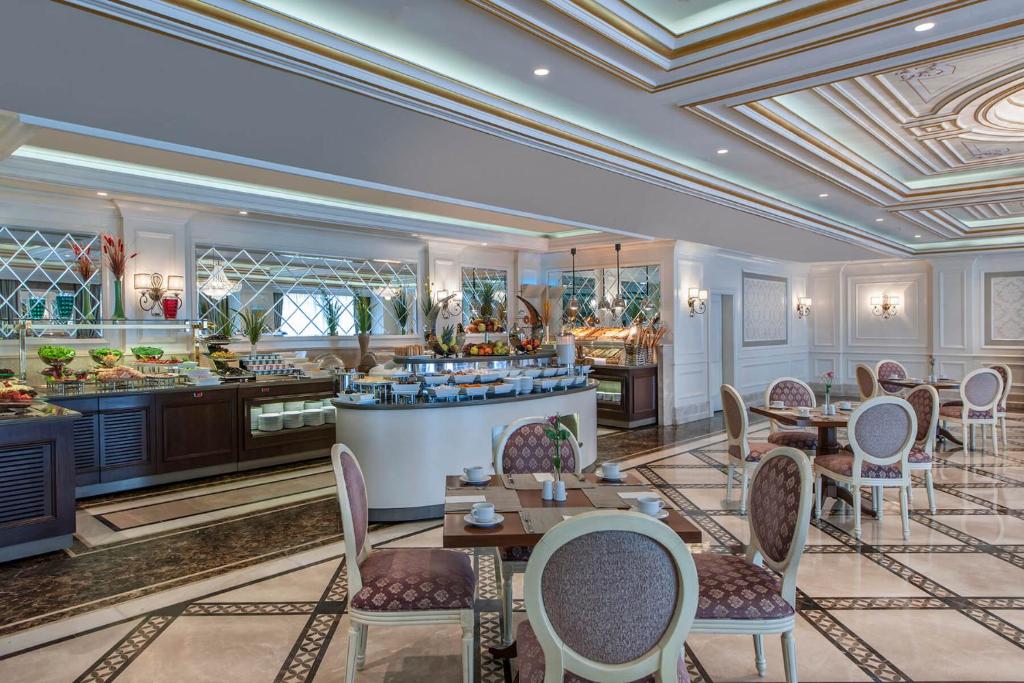 a dining room with tables and chairs and a kitchen at Elite World Istanbul Florya in Istanbul