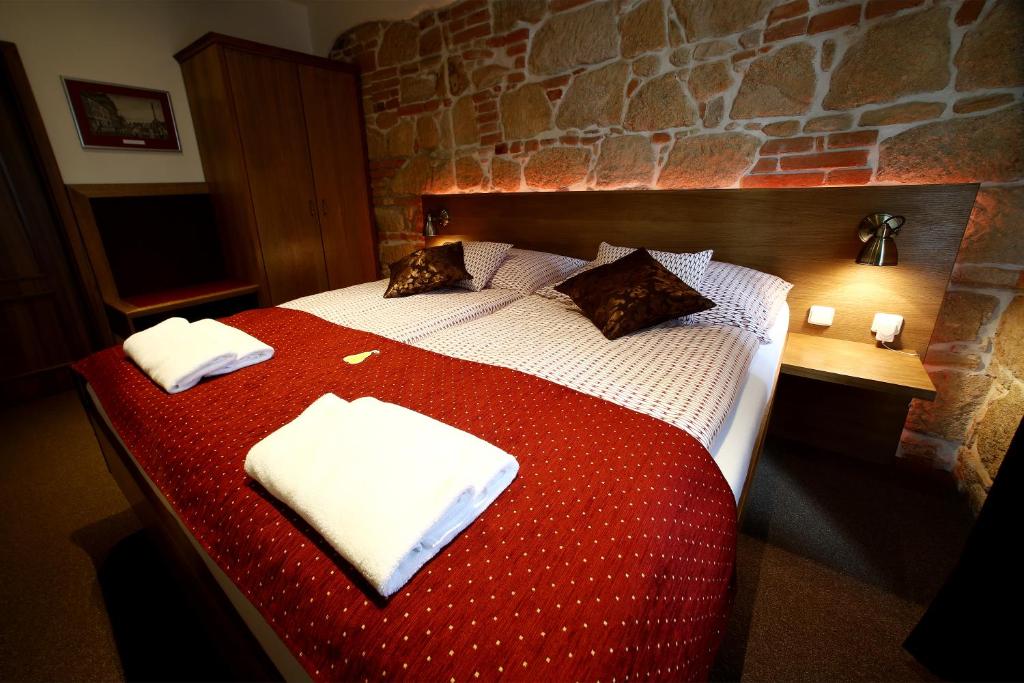 プルゼニにあるApartments & Suites Žlutá Hruškaのベッドルーム1室(赤と白のベッド1台、タオル2枚付)