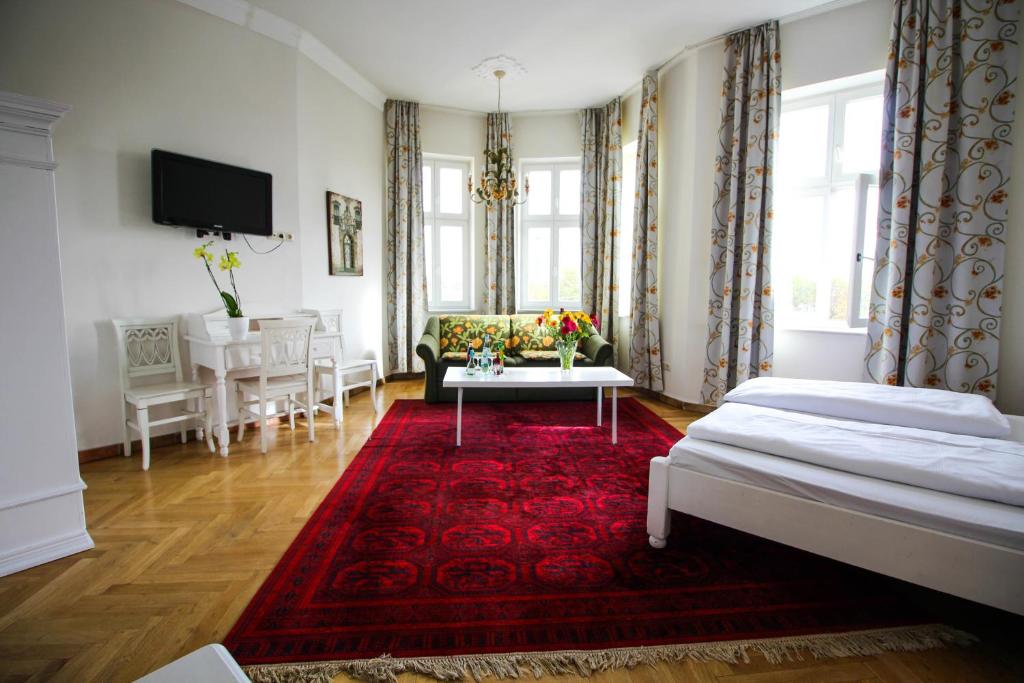 a living room with two beds and a red rug at Hotel Seibel in Munich